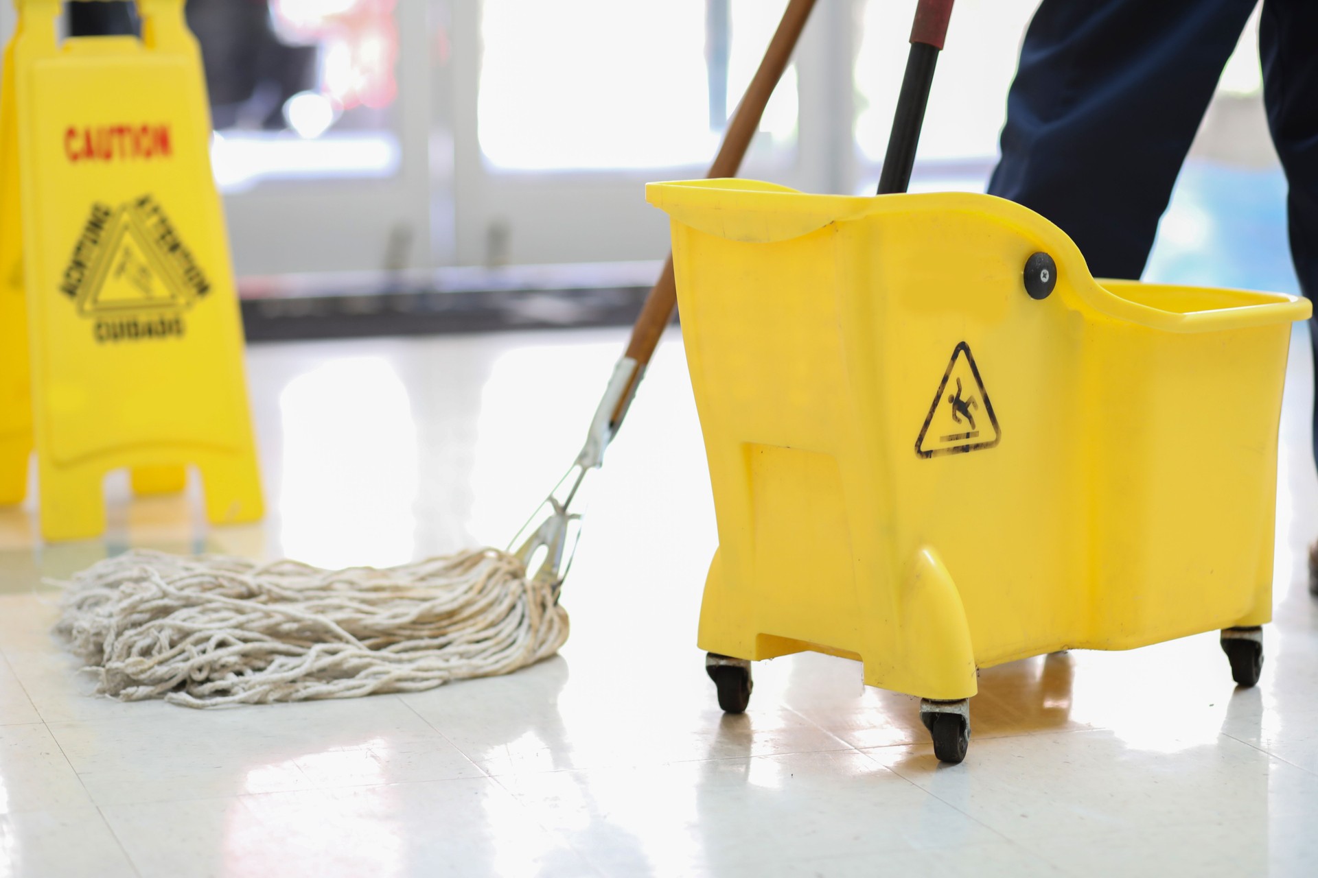 Unrecognizable male janitor mopping floor in office building.